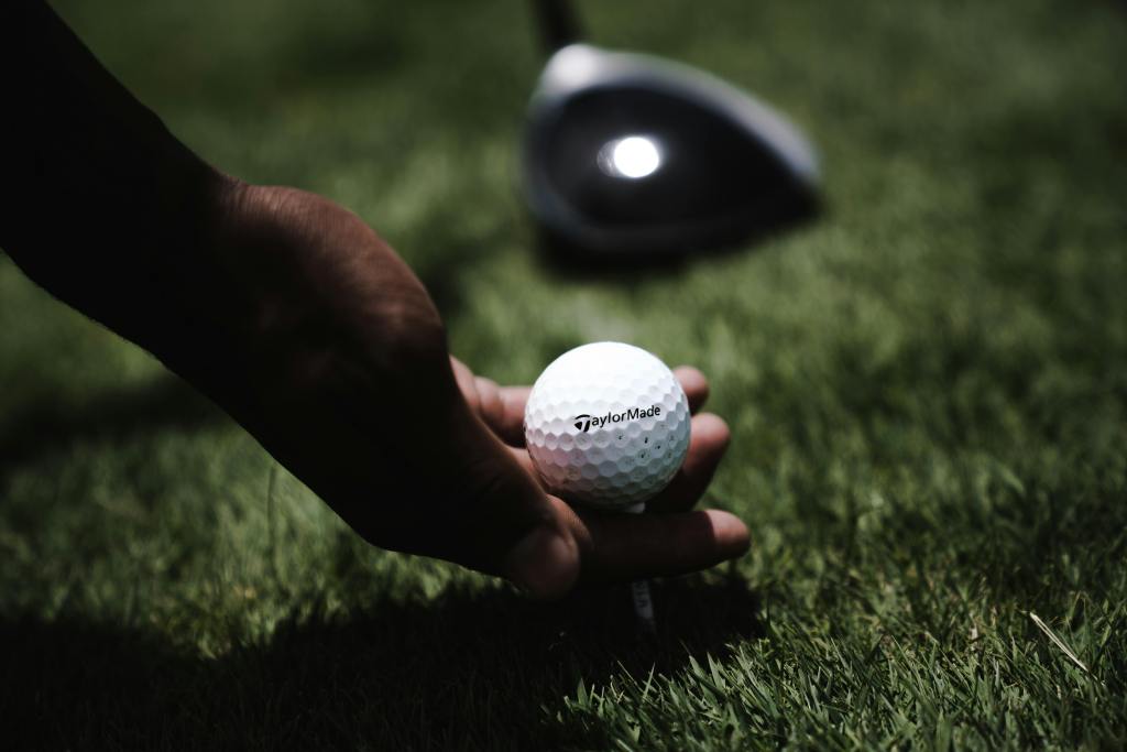 Golfer placing tee with golf ball on golf course 